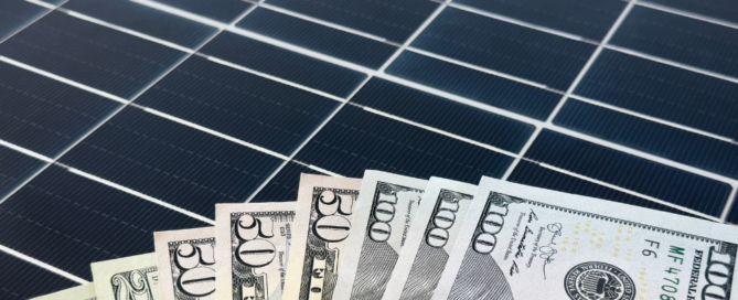 A fan of U.S. dollar bills is placed on top of a solar panel.