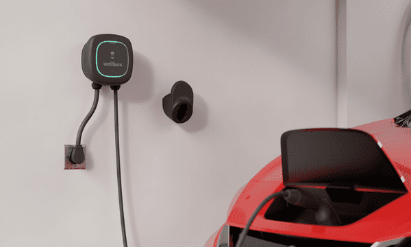 A Wallbox is charging an EV in the garage of a home.