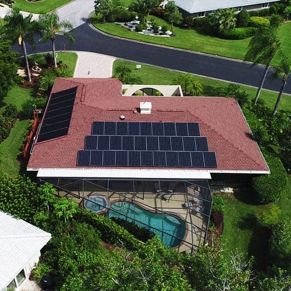 Mirasol Solar residential solar panel installation on red roof home with screened pool and lush landscaping