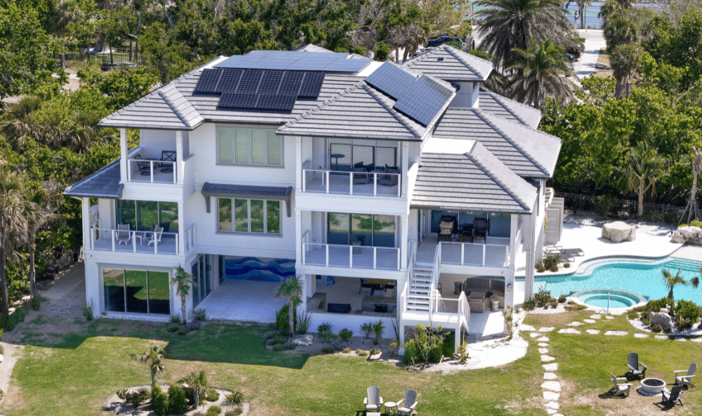 Angled aerial view of the Judge Residence showing multiple solar arrays integrated into the roofline, designed and installed by Mirasol Solar to meet 180 MPH wind load requirements.